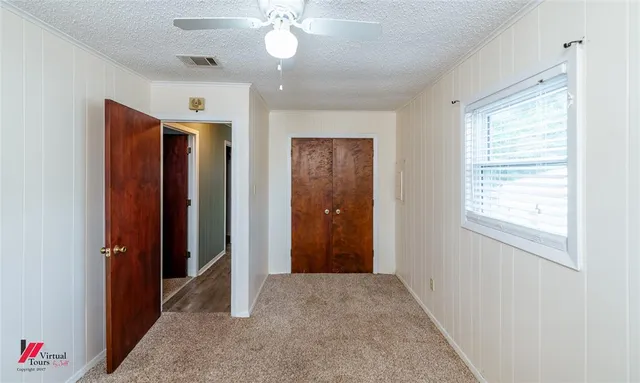 an empty room with a chandelier fan and windows