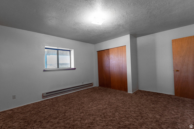1208 East Tidwell Road Loa, UT 84747 - Photo 35 of 40 Unfurnished bedroom featuring a baseboard radiator, a textured ceiling, a closet, and carpet flooring