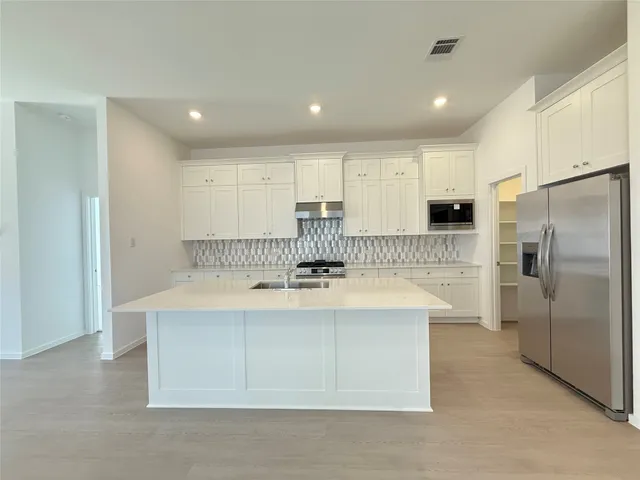 a kitchen with kitchen island a white cabinets and refrigerator