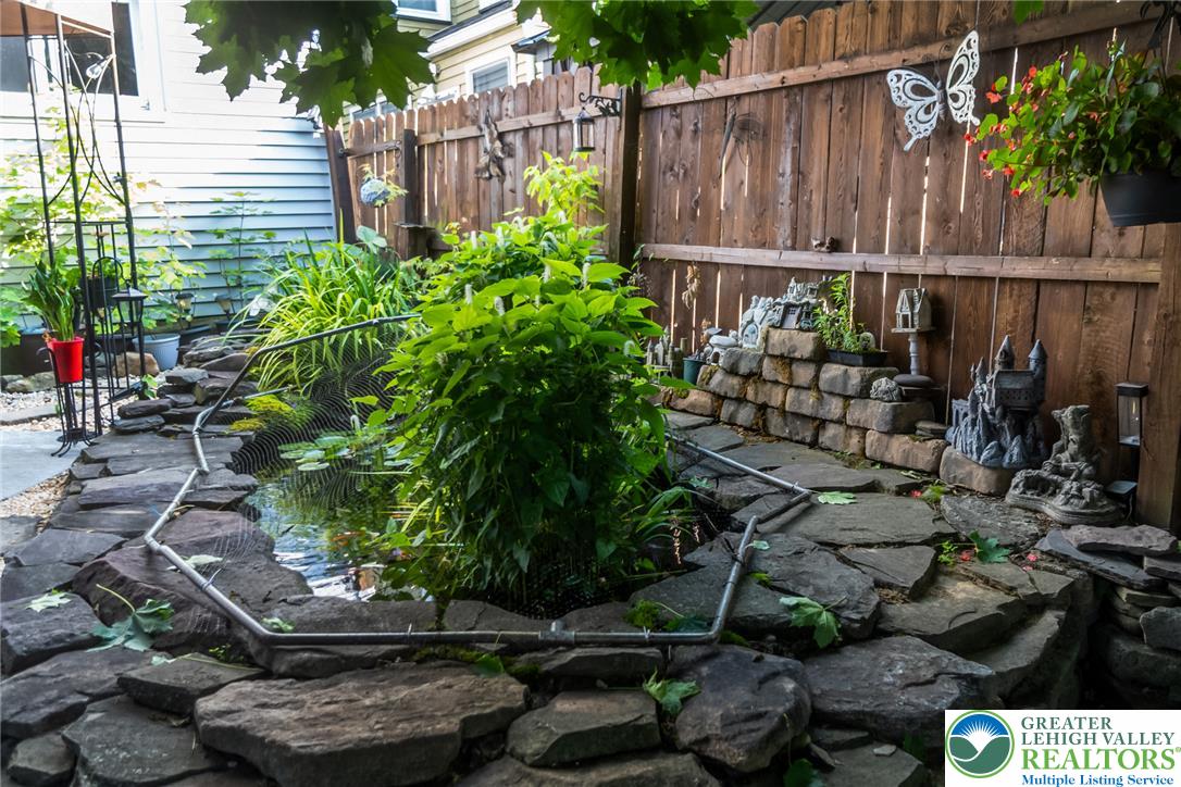 365 Rock Street Easton, PA 18042 - Photo 50 of 50 A tranquil water feature with natural stone edging, nestled against a sturdy wooden fence.