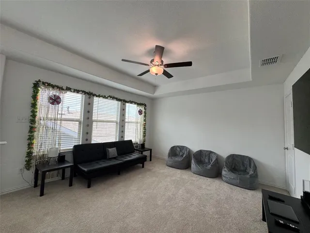 a living room with furniture a ceiling fan and a flat screen tv
