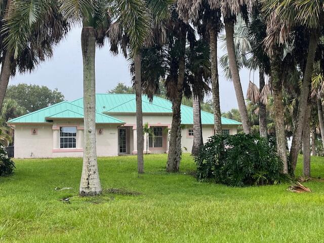 a view of a white house with a big yard and palm trees