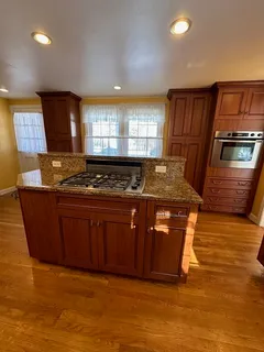 a kitchen with granite countertop wooden cabinets stove and sink