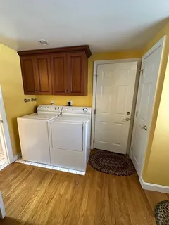 a utility room with wooden floor washer and dryer