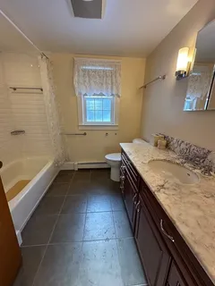 a bathroom with a granite countertop sink a toilet and bathtub