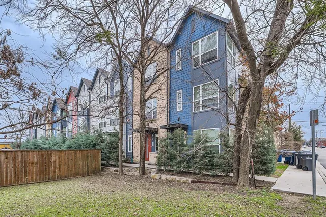 a view of a brick house next to a yard with wooden fence