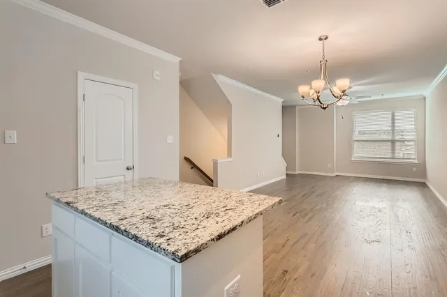 a kitchen with stainless steel appliances granite countertop a stove a sink dishwasher a refrigerator and white cabinets with wooden floor