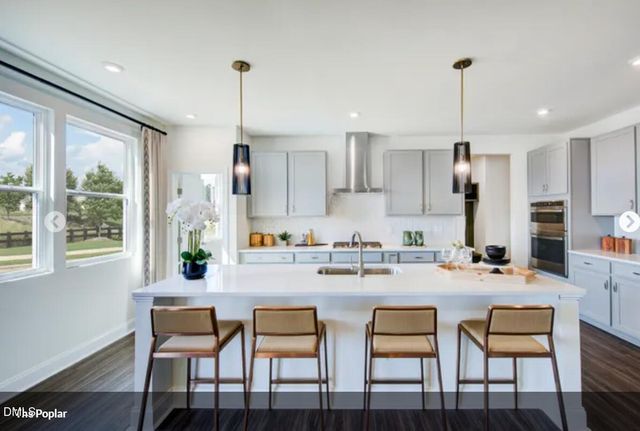 a kitchen with stainless steel appliances a dining table chairs stove and white cabinets