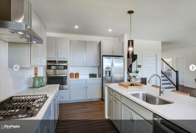 a kitchen with stainless steel appliances kitchen island granite countertop a sink stove and refrigerator