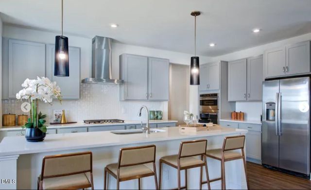 a kitchen with granite countertop a counter space chairs stainless steel appliances and cabinets