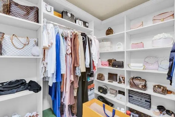 a view of walk in closet with clothes and shoes