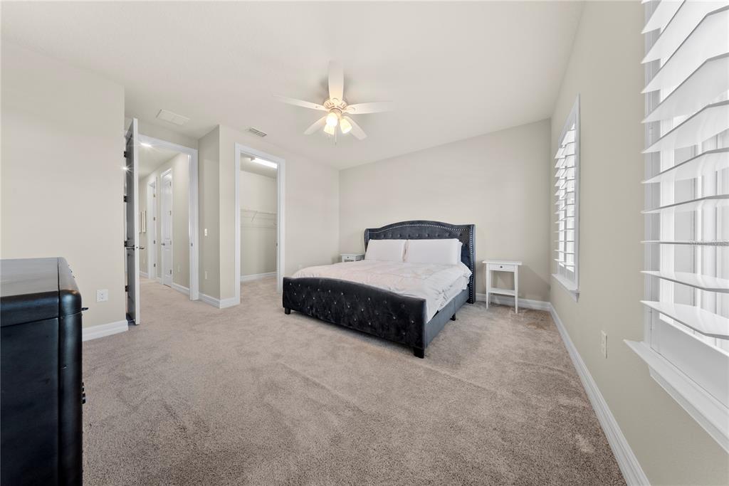 7905 Wandering Way Orlando, FL 32836 - Photo 45 of 70 a spacious bedroom with a bed and a chandelier