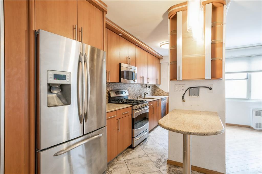 2944 West 5th Street, Unit 14F Brooklyn, NY 11224 - Photo 8 of 13 a kitchen with stainless steel appliances granite countertop a refrigerator a stove and a sink with large window
