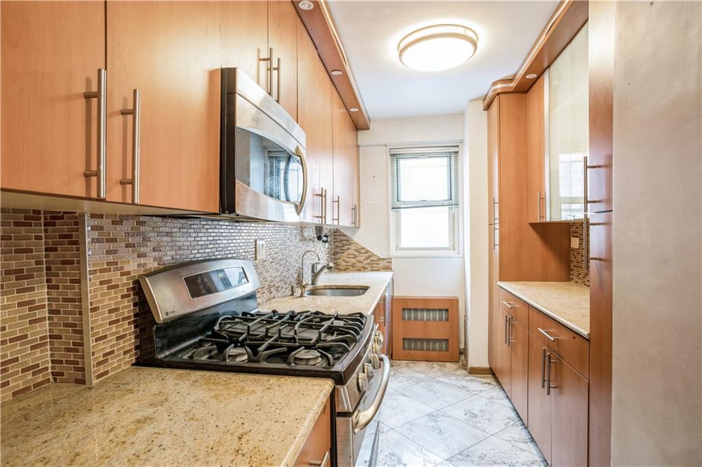 2944 West 5th Street, Unit 14F Brooklyn, NY 11224 - Photo 9 of 13 a kitchen with stainless steel appliances granite countertop a stove a sink and a refrigerator