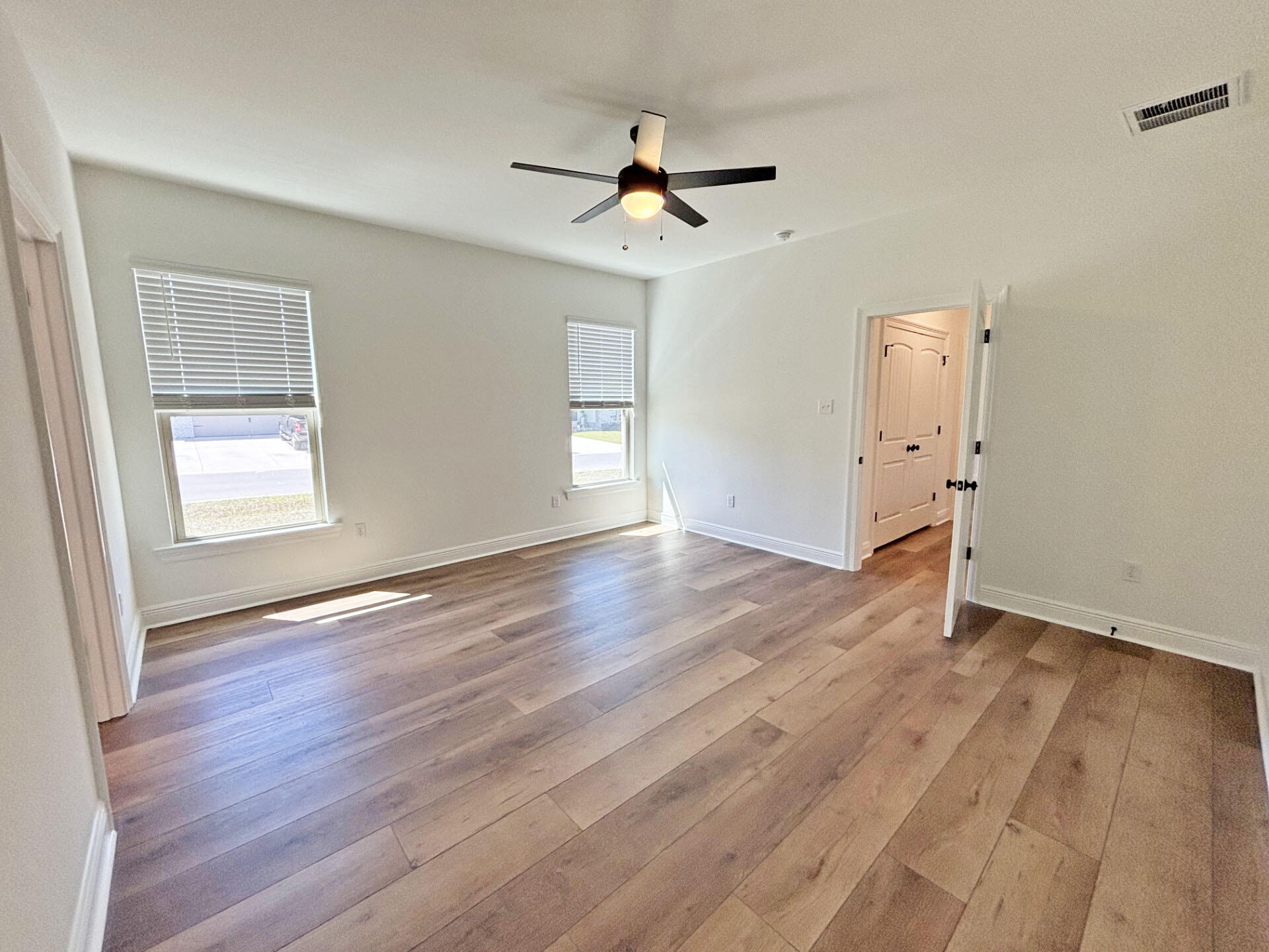 2731 Louis Circle Crestview, FL 32536 - Photo 9 of 17 an empty room with wooden floor a ceiling fan and windows