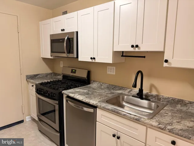 a kitchen with stainless steel appliances granite countertop a sink stove and white cabinets