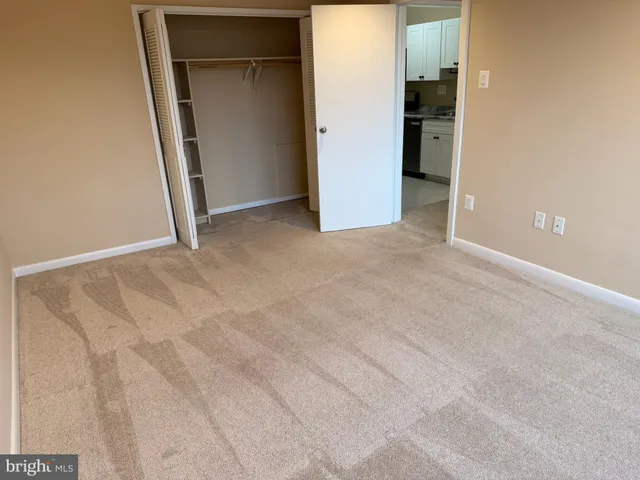 an empty room with closet and a hallway