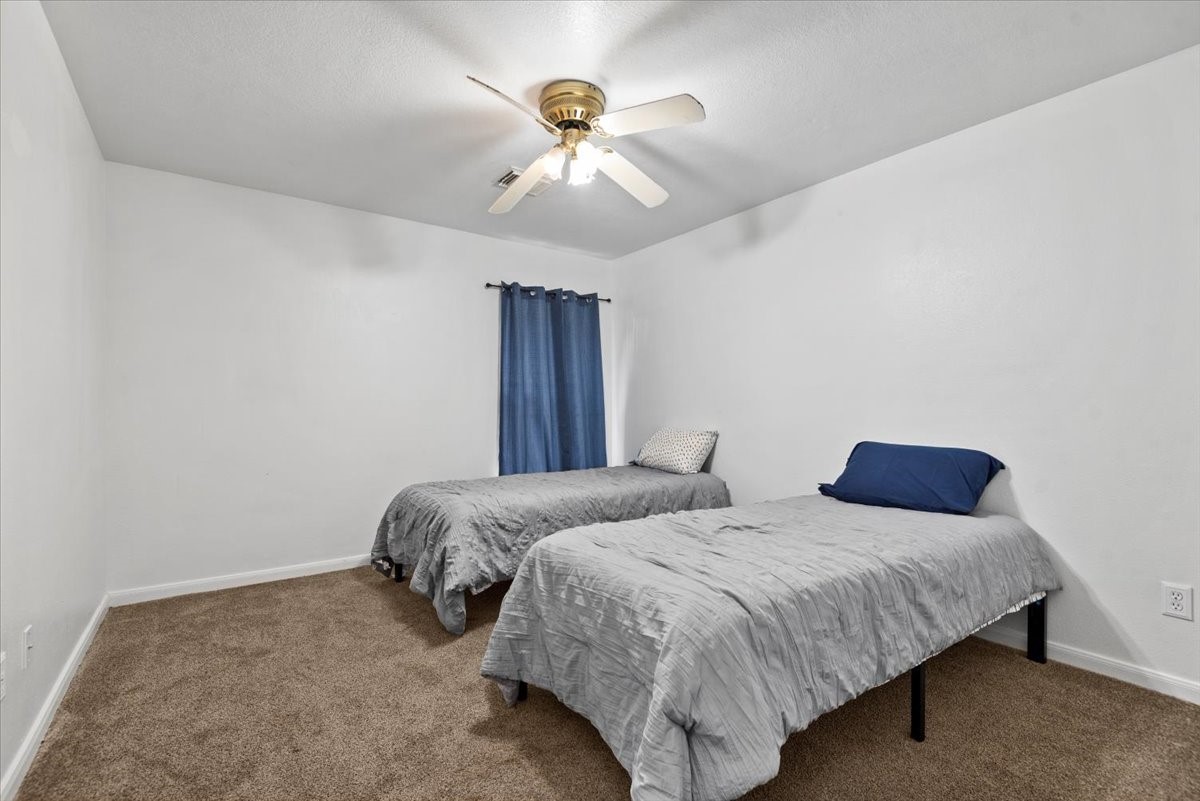 22711 Tree House Lane Spring, TX 77373 - Photo 21 of 28 a bedroom with two large bed and a ceiling fan