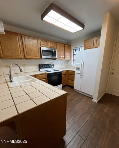 a kitchen with stainless steel appliances a stove a sink a microwave a refrigerator a cabinets and wooden floor