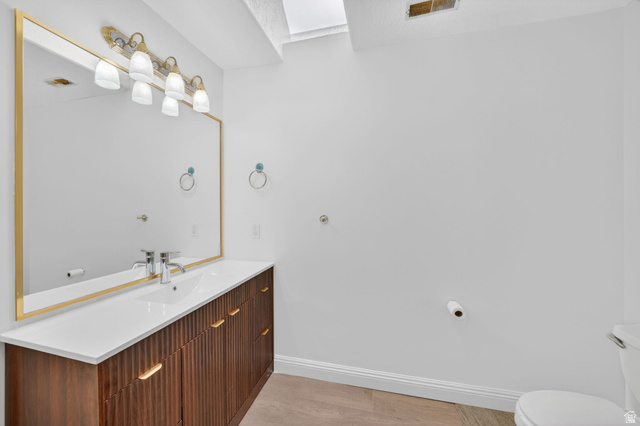 883 East 700 South Springville, UT 84663 - Photo 28 of 59 Spacious bathroom featuring a wood-finish vanity with integrated sink, a large gold-framed mirror, a five-light vanity fixture, and a skylight