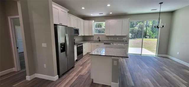 a kitchen with a refrigerator a sink and wooden floor
