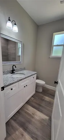 a bathroom with a granite countertop sink a toilet and mirror