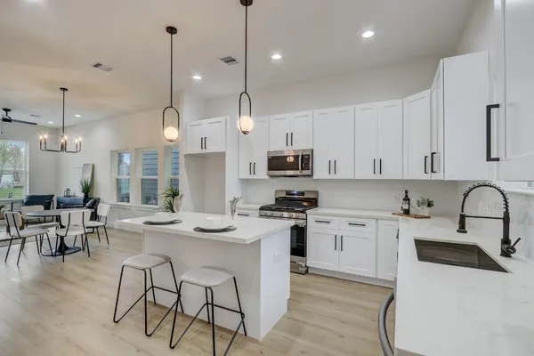 a kitchen with stainless steel appliances kitchen island a white table chairs and a stove