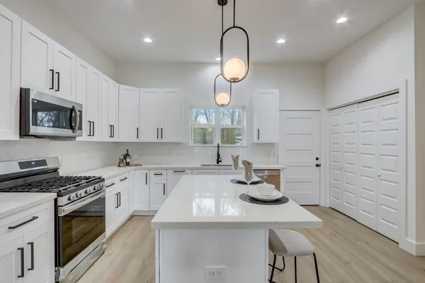 a kitchen with kitchen island granite countertop a sink cabinets and wooden floor