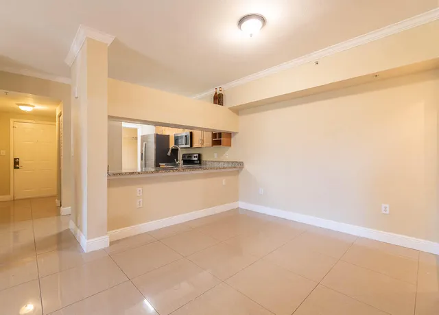 a view of a refrigerator in kitchen and an empty room