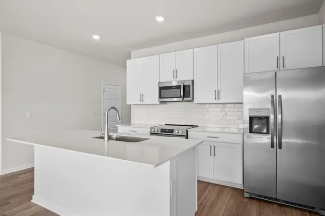 a kitchen with stainless steel appliances a sink a stove a refrigerator and cabinets