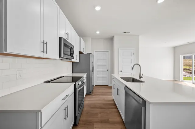 a kitchen with stainless steel appliances granite countertop a sink stove refrigerator and cabinets