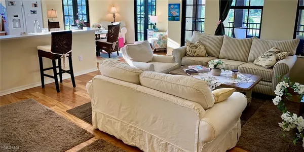 a living room with furniture and a dining table with wooden floor