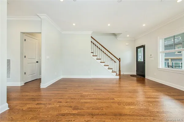 a view of an empty room with wooden floor and windows