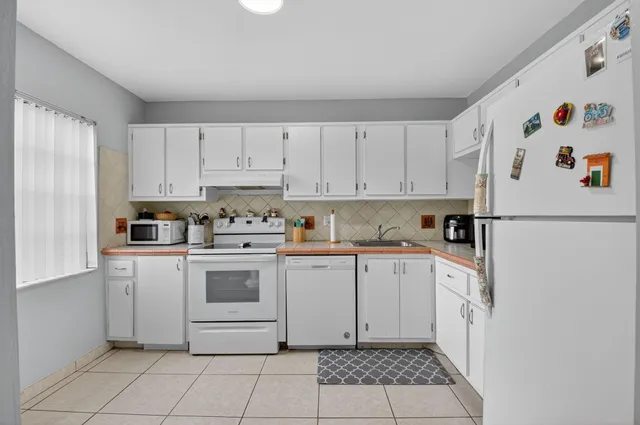 a kitchen with white cabinets and white appliances