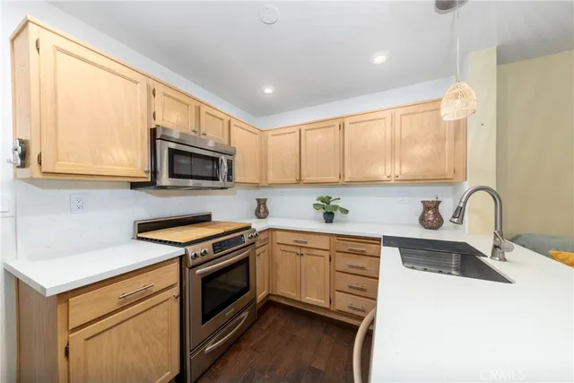 a kitchen with stainless steel appliances granite countertop white cabinets a sink a stove a window and a microwave