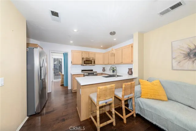 a living room with stainless steel appliances kitchen island granite countertop furniture and a wooden floor