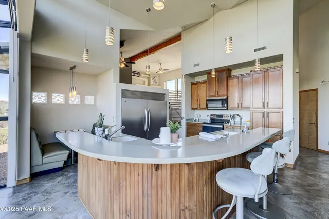 a kitchen with stainless steel appliances kitchen island granite countertop a sink a refrigerator and blue cabinets