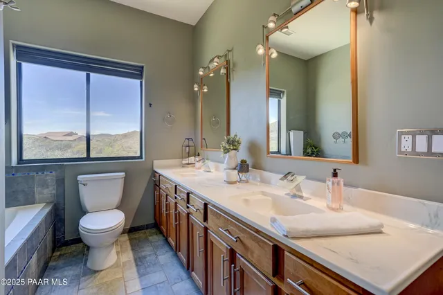 a bathroom with a granite countertop sink toilet a large mirror a vanity and a window
