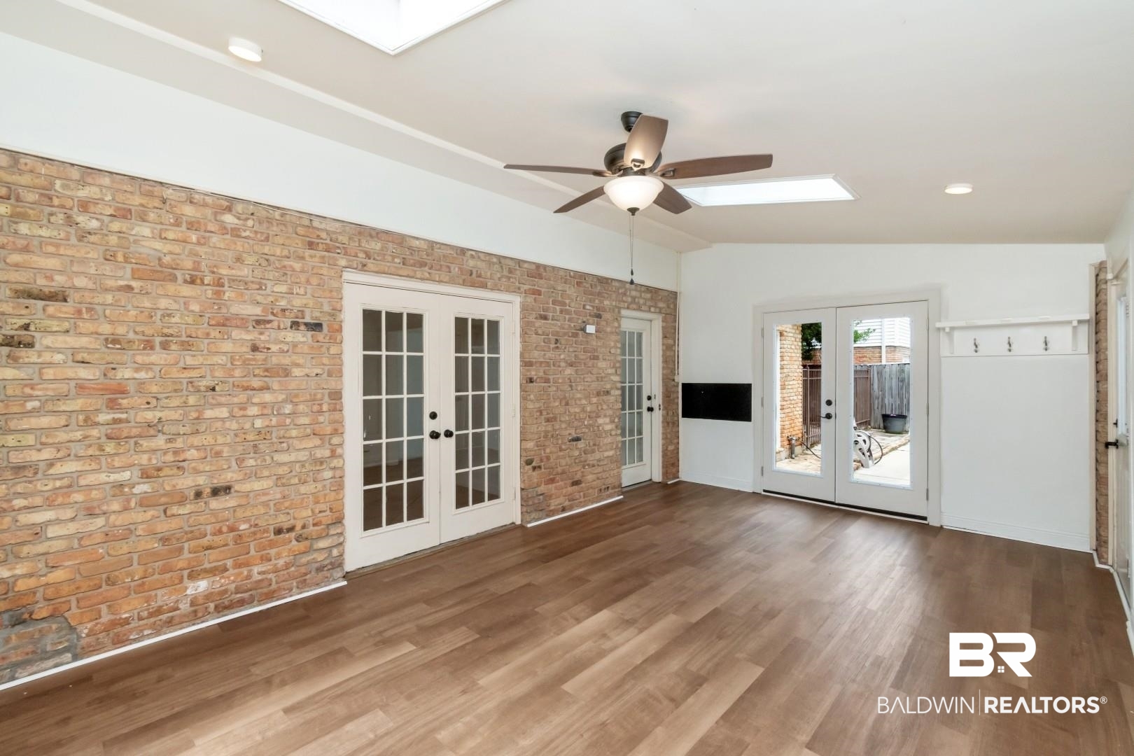 3755 Claridge Road North Mobile, AL 36608 - Photo 16 of 38 Spare room featuring french doors, a skylight, brick wall, a ceiling fan, and lofted ceiling
