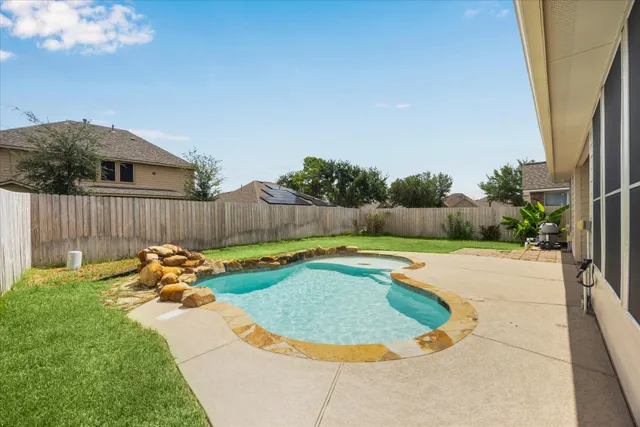 a view of a backyard with swimming pool and furniture