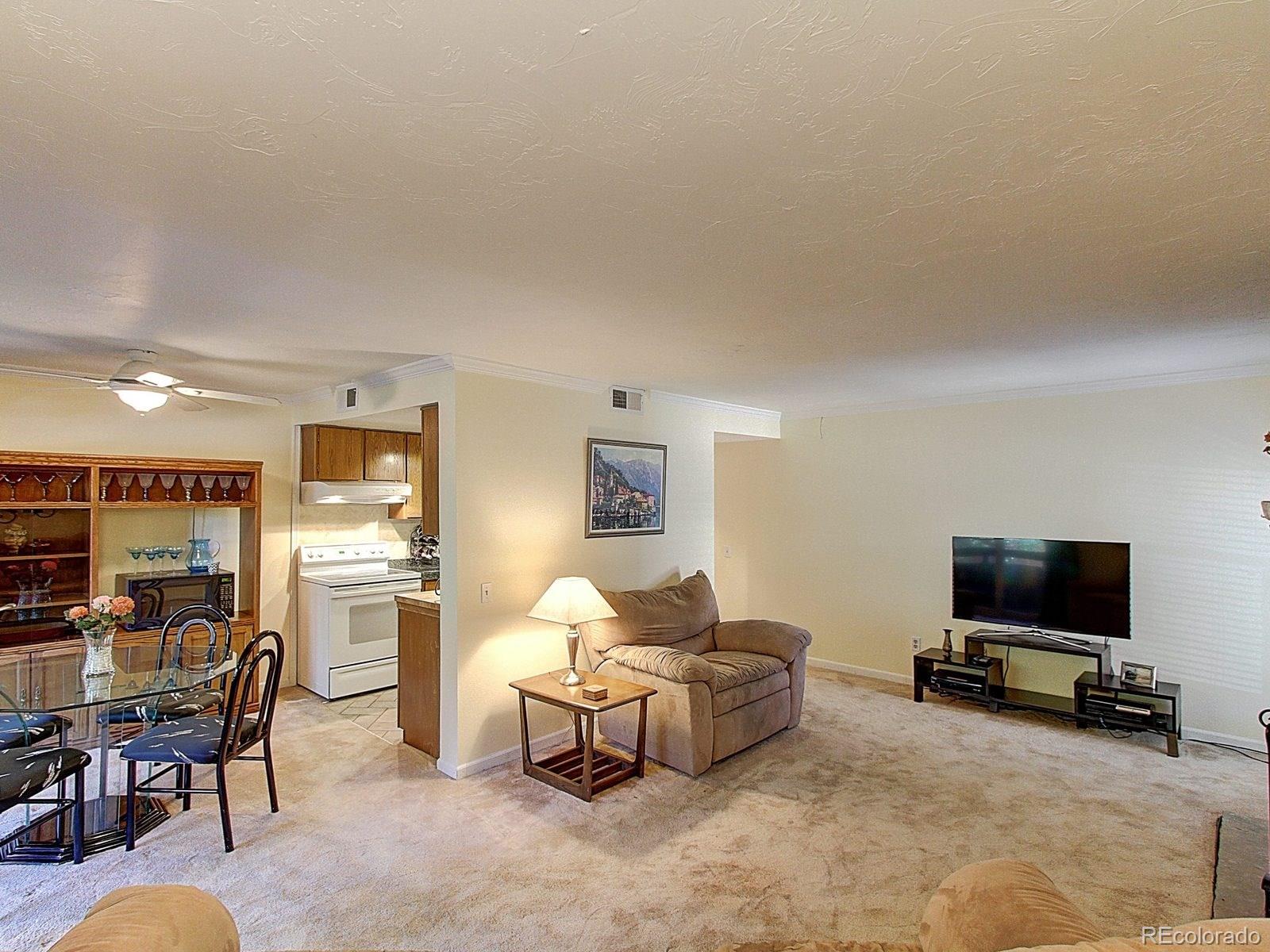 6410 South Dayton Street, Unit I08 Englewood, CO 80111 - Photo 4 of 32 a living room with furniture a flat screen tv and a table