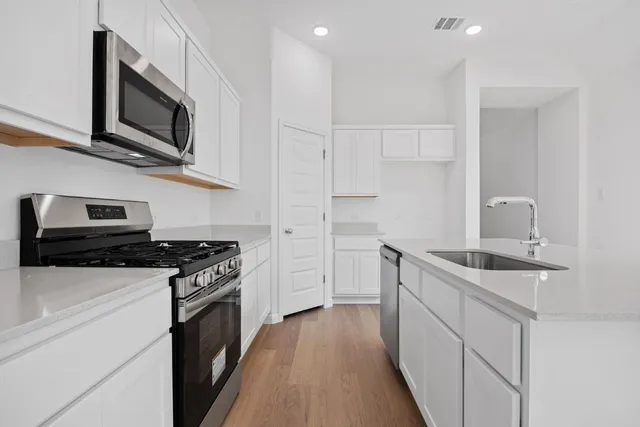 a kitchen with stainless steel appliances granite countertop a stove a sink and a microwave