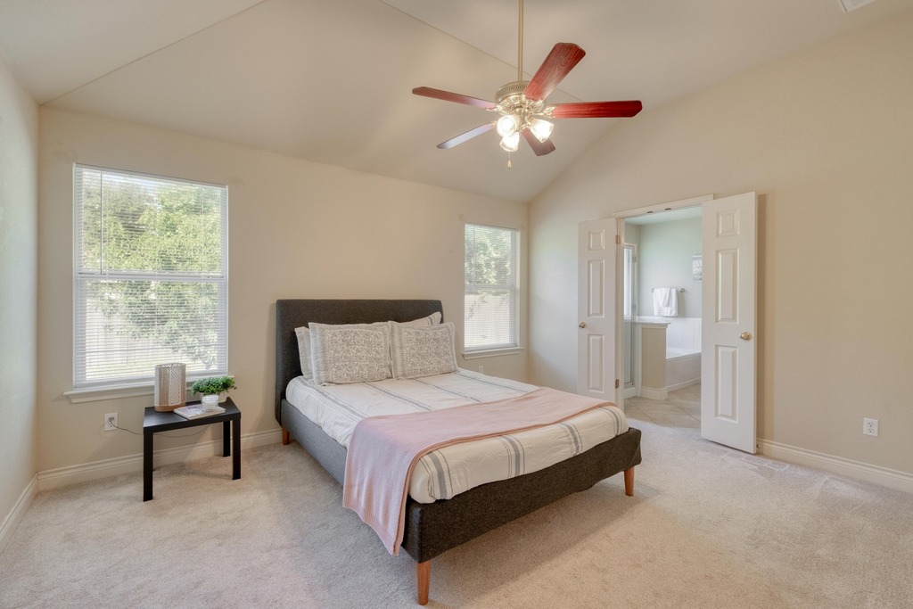 1303 Ridgewood Drive Leander, TX 78641 - Photo 12 of 28 a spacious bedroom with a bed and a chandelier