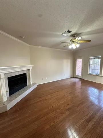 a view of an empty room with wooden floor fireplace and a window
