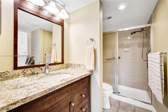 a bathroom with a granite countertop sink toilet mirror and shower
