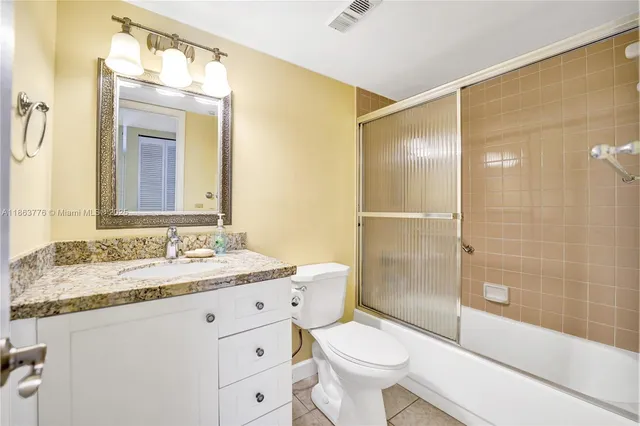 a bathroom with a granite countertop sink toilet mirror and shower