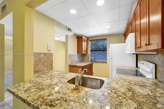 a kitchen with granite countertop a sink stainless steel appliances a counter top space and cabinets
