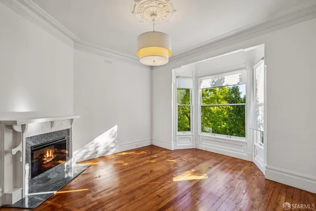 a view of an empty room with window and wooden floor