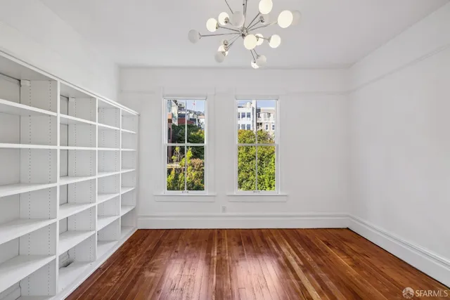 a view of an empty room with a window and wooden floor