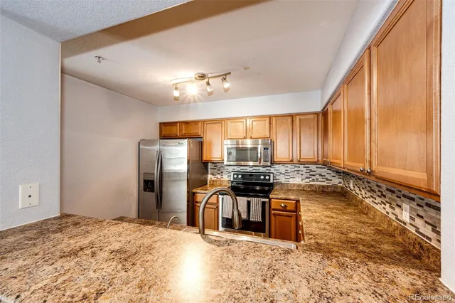 a kitchen with stainless steel appliances granite countertop a stove a refrigerator and a stove